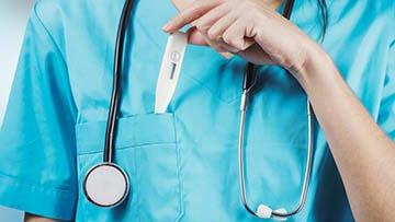 Person putting thermometer in pocket of scrubs